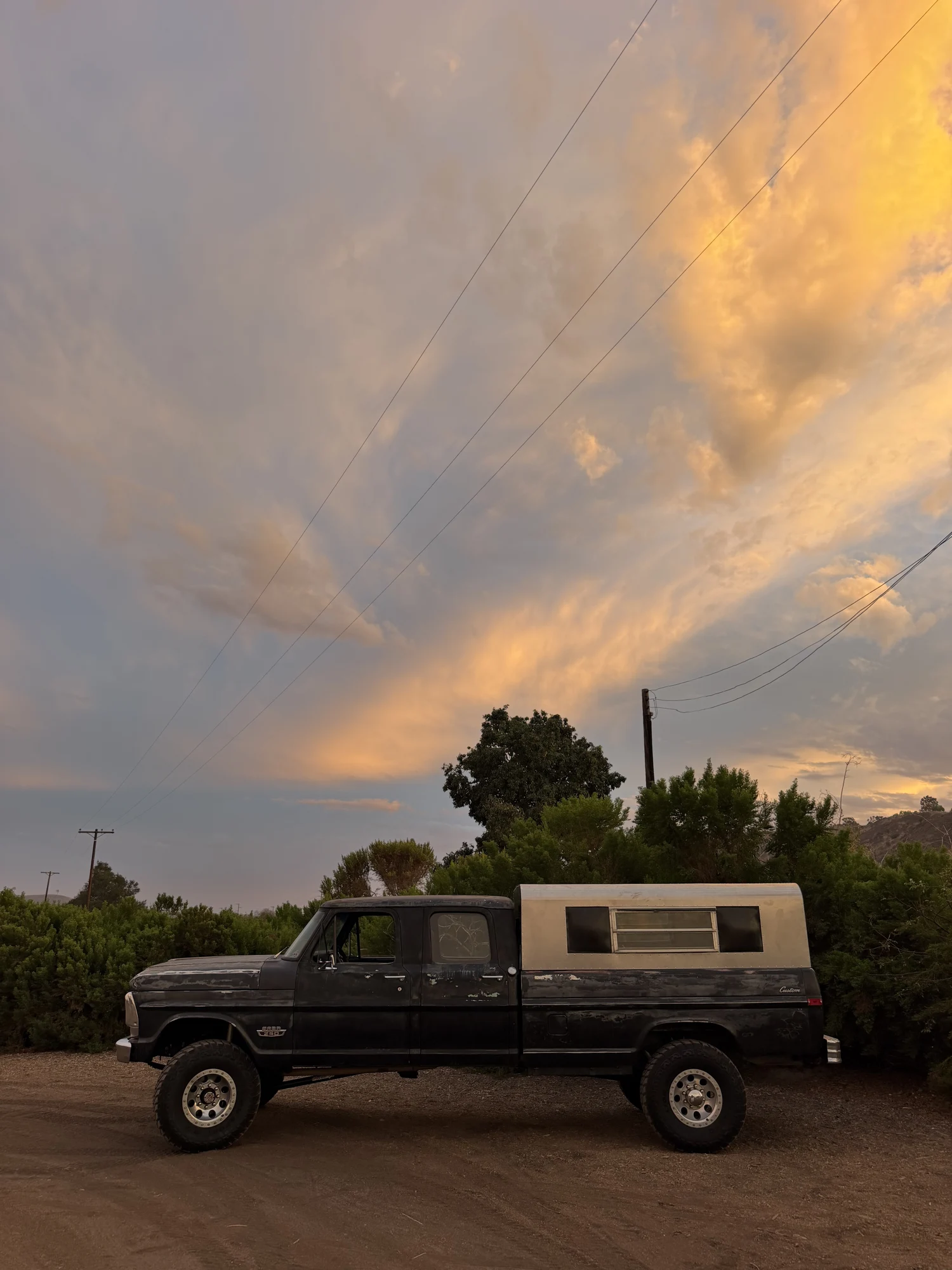 Vintage Ford truck with a custom aluminum camper shell under a California sunset
